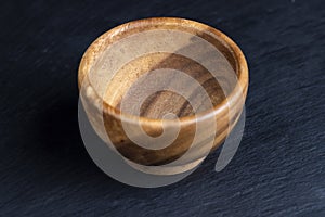 an empty wooden bowl on a black slate table