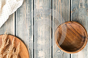 Empty wooden bowl on rustic gray wooden table surface with tray of spikelets and white towel. Copy space. Top view