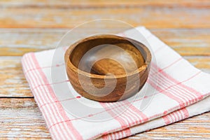 Empty wooden bowl on tablecloth napery on dining table / natural kitchen products