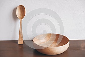 Empty wooden bowl and wooden spoon on a brown table background. Copy, empty space for text