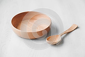 Empty wooden bowl and wooden spoon on a white table background