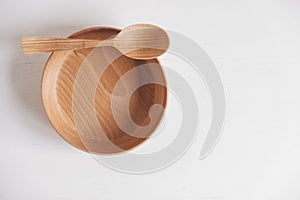 Empty wooden bowl and wooden spoon on a white table background. Top view. Copy, empty space for text