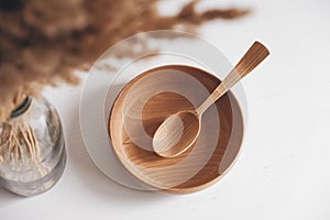 Empty wooden bowl and wooden spoon on a white table background. Top view. Copy, empty space for text