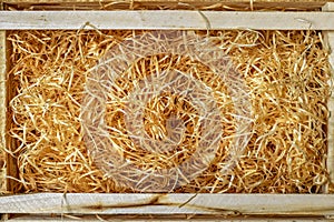 An empty wooden box filled with decorative wood shavings.