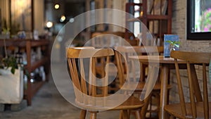 Empty wooden chair in a cozy coffee shop, with a blurred background of tables, chairs, and cafe interior.