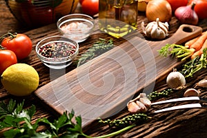 Empty wooden cutting board with copy space surrounded by peppers, herbs, tomatoes, mushrooms and other delicious flavoured vegetab