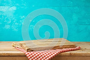 Empty wooden cutting board on kitchen table with tablecloth over