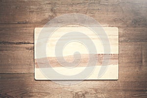 Empty wooden cutting board on a wood background.