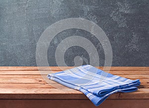 Empty wooden deck table with blue cheched tablecloth over blackboard background for product montage