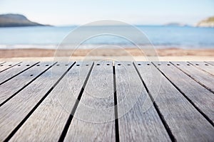 Empty wooden deck table on blurry sea and beach background