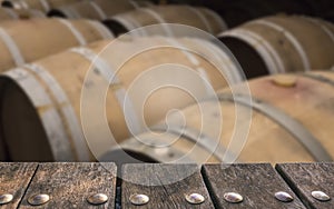 Empty wooden deck table on blurry winery barrels background. Can be used for mockup products displays