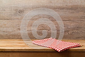 Empty wooden deck table with checked red tablecloth over wooden wall background for product montage