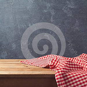 Empty wooden deck table with checked tablecloth over blackboard background