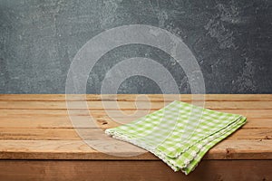 Empty wooden deck table with checked tablecloth over blackboard background