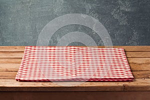 Empty wooden deck table with checked tablecloth over blackboard background for product montage