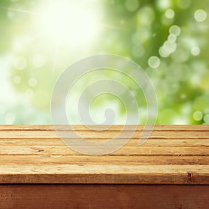 Empty wooden deck table with foliage bokeh