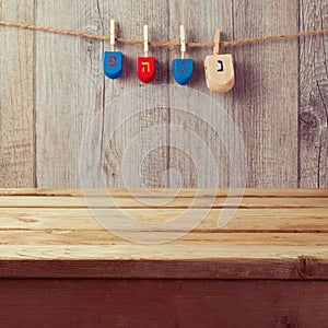 Empty wooden deck table with Hanukkah dreidel spinning top hanging on string