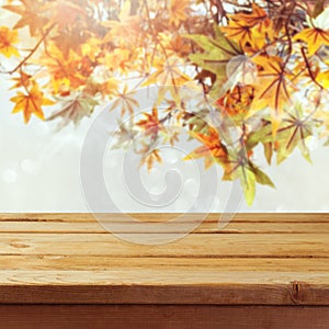 Empty wooden deck table over autumn leaves bokeh background
