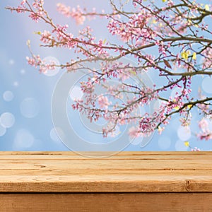 Empty wooden deck table over blurred bokeh spring tree background for product montage