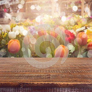 Empty wooden deck table over blurred tulip flowers background for product montage display. Spring