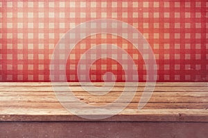 Empty wooden deck table over checked red wallpaper. Vintage kitchen interior.