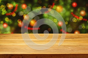 Empty wooden deck table over Christmas tree bokeh background