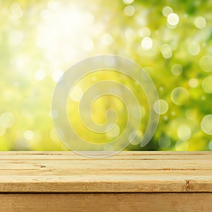 Empty wooden deck table over green bokeh. Spring background for product montage