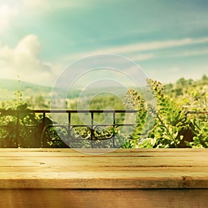 Empty wooden deck table over summer landscape background for product montage display. Retro filter