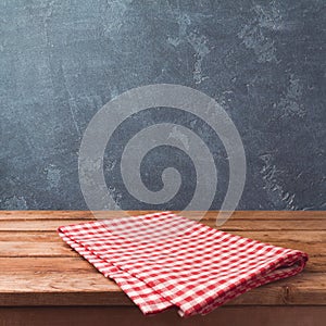 Empty wooden deck table with red cheched tablecloth over blackboard background for product montage display.
