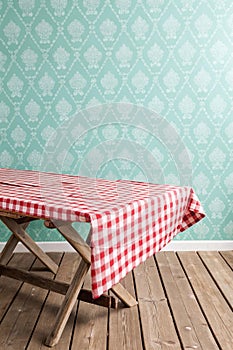 Empty wooden deck table and red checked tablecloth over mint wallpaper background