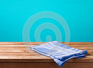 Empty wooden deck table with tablecloth over blue wall background for product montage