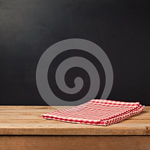 Empty wooden deck table with tablecloth over chalkboard background