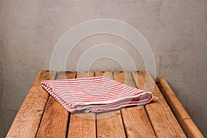 Empty wooden deck table with tablecloth over rustic background