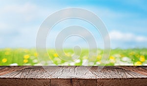 Empty wooden desk with empty space for product display over blurred green field background. Summer, nature, ecology or