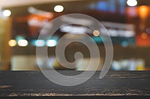 empty wooden desk over blurred coffee shop cafe background