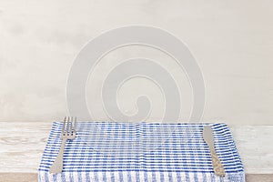 Empty wooden desk table and red checked tablecloth over gray wallpaper background