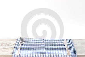 Empty wooden desk table and red checked tablecloth over gray wallpaper background
