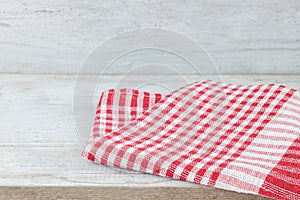 Empty wooden desk table and red checked tablecloth over mint wallpaper background
