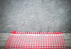 Empty wooden desk table and red checked tablecloth over mint wallpaper background