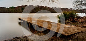 Empty wooden dock leading into a smooth lake