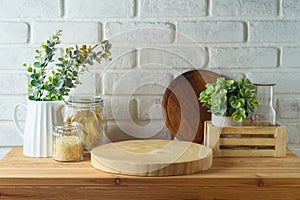 Empty wooden log on kitchen table with food jars and plants over white brick wall background. Kitchen mock up for design and