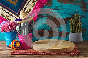 Empty wooden log on table with cactus decoration over blue wall background. Mexican party mock up for design and product display