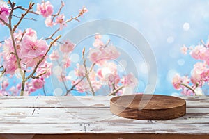 Empty wooden log on table over cherry blossom flowers background. Spring and Easter mock up for design and product display