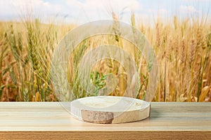 Empty wooden log on table over wheat field background. Jewish holiday Shavuot mock up for design and product display