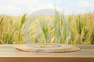 Empty wooden log on table over wheat field background. Jewish holiday Shavuot mock up for design and product display