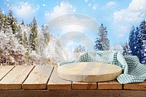 Empty wooden log with tablecloth on rustic table over winter landscape background.  Christmas and New Year mock up for design and