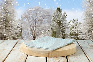 Empty wooden log with tablecloth on rustic table over winter landscape background.  Christmas and New Year mock up for design and