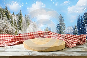 Empty wooden log with tablecloth on table over winter landscape background.  Christmas holiday mock up for design and product