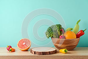 Empty wooden log with vegetables and fruits on table over blue wall  background. Vegetarian kitchen interior mock up for design