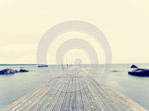 Empty wooden mole in water of blue lake. Old fishing wharf for hired boats and swimmers.